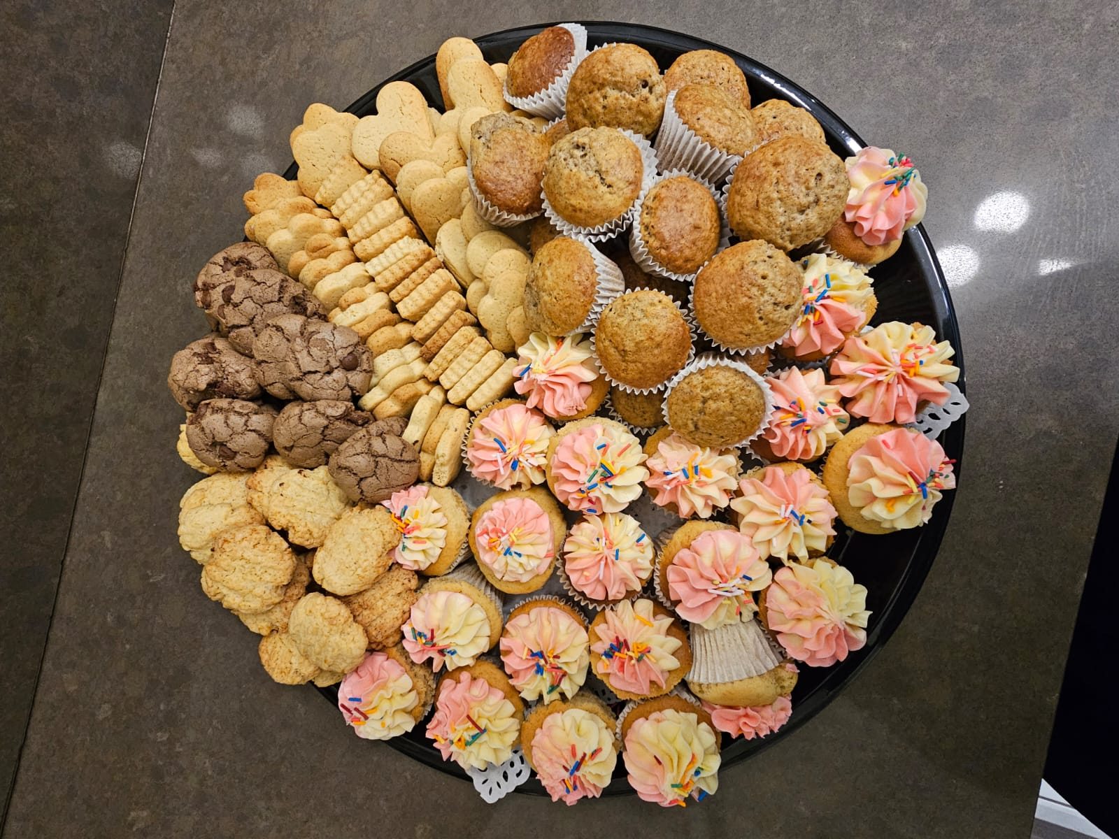 A celebration platter filled with cupcakes, muffins and assorted biscuits